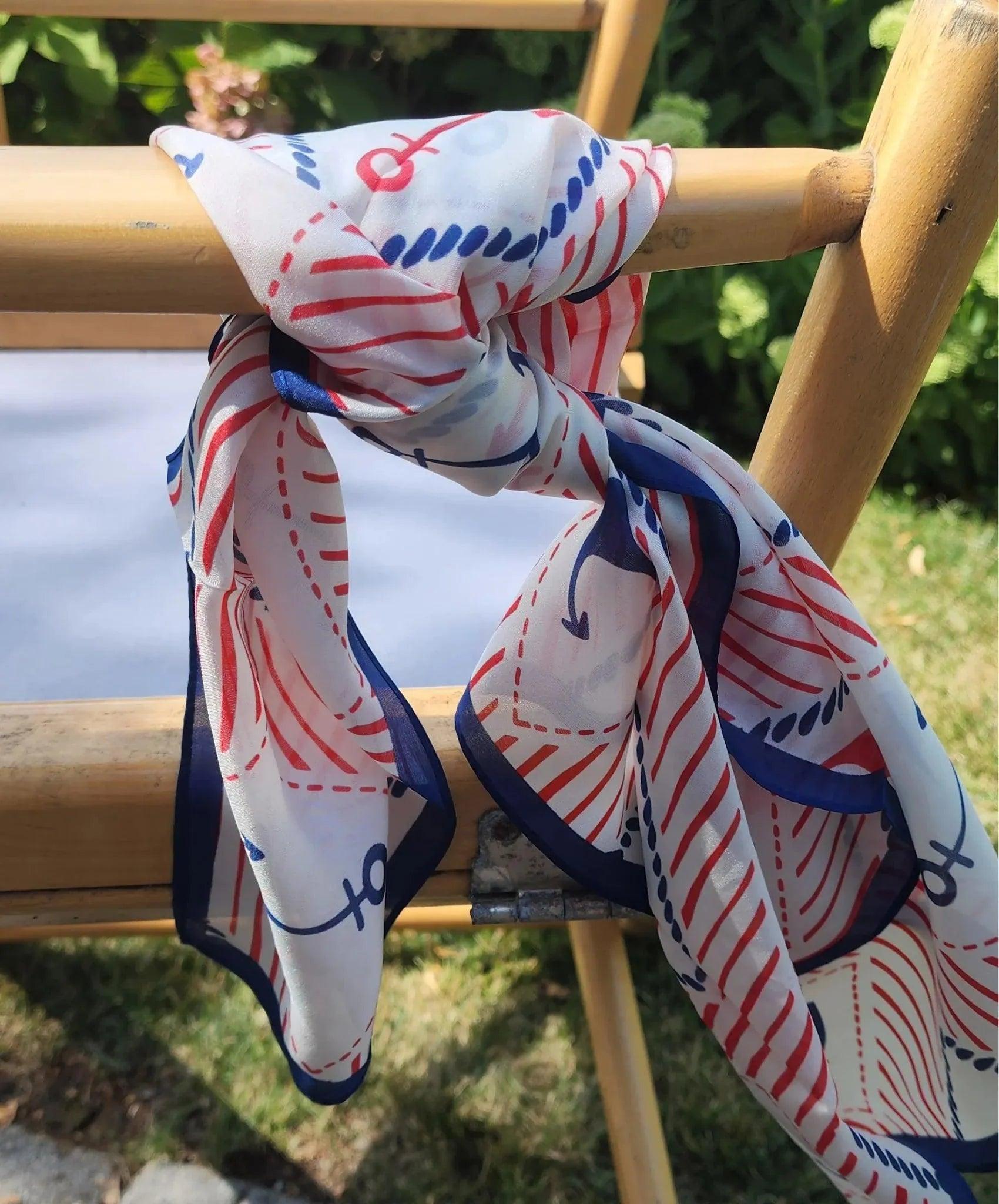 close up picture of a silk scarf tied. Red, white and blue colors with anchor designs.