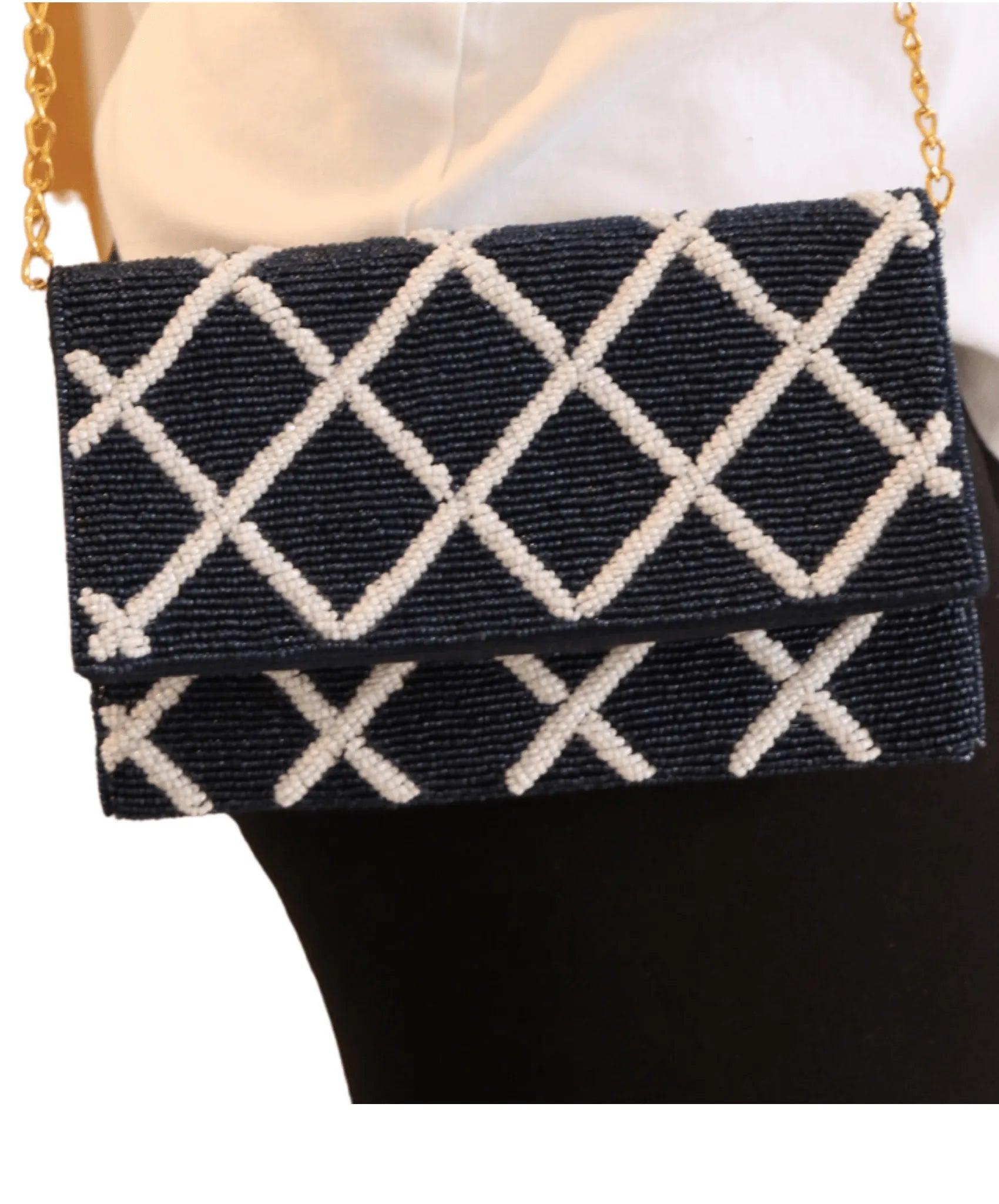 picture of navy and white lattice trim bag on persons shoulde3r with chain hanging down.