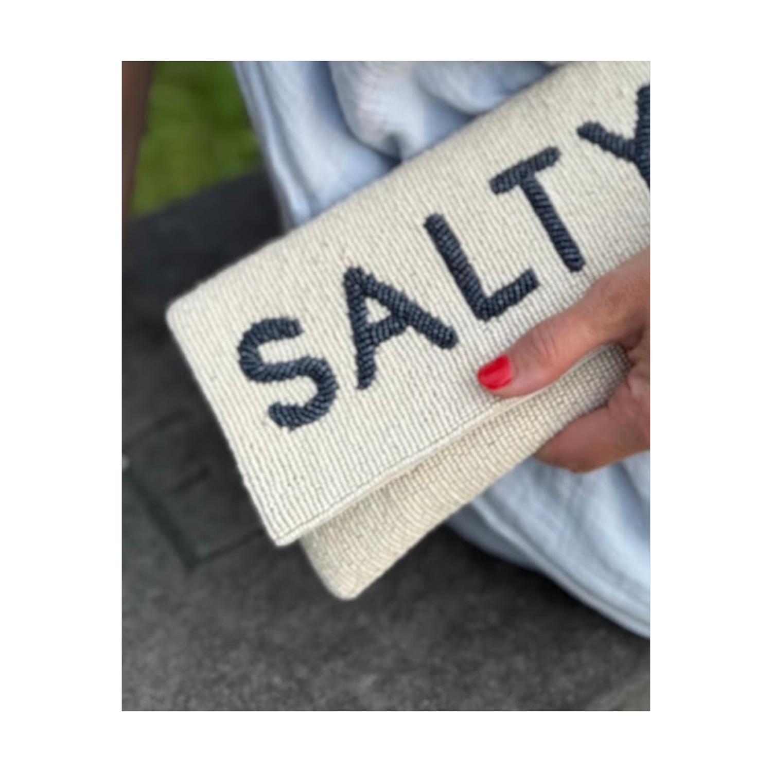 Close-up view of cream beaded clutch with Salty lettering in navy