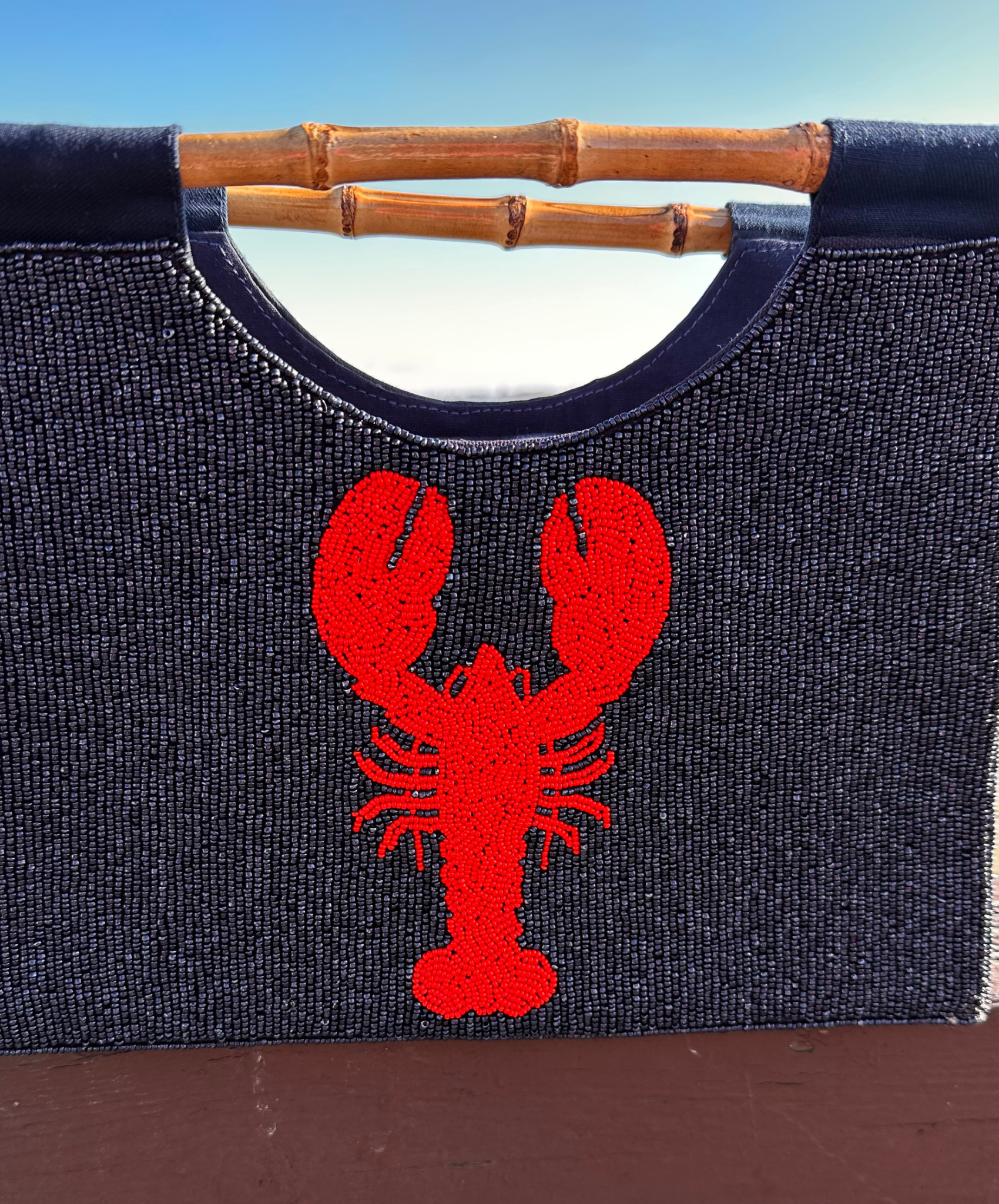 close Up of Navy Purse with REd Lobster Design and straight bamboo handles.  