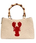 Cream handbag with a red lobster design and wooden handle on a white background