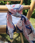 close up picture of a silk scarf tied.  Red, white and blue colors with anchor designs. 
