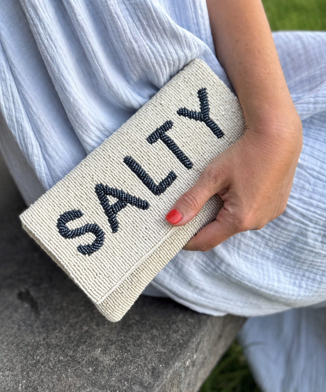 cream beaded clutch with navy SALTY lettering handheld outdoors