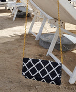 picture of navy clutch with white lattice hanging from chair. 